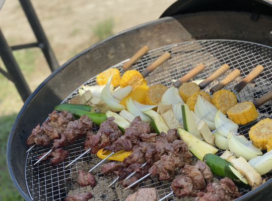 BBQコンロで肉と野菜の串が焼かれている写真