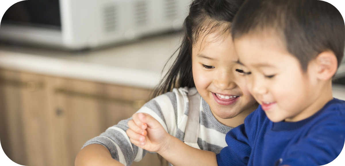 女の子と男の子が笑顔で一緒に料理を楽しんでいる様子